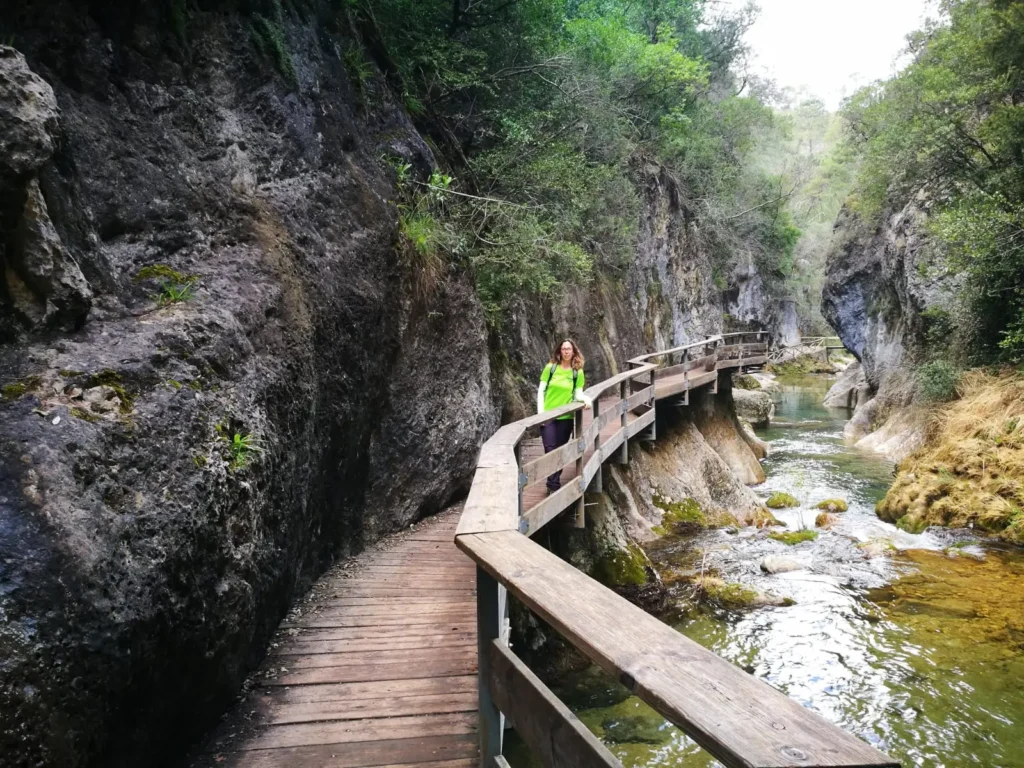 Senderista recorriendo una pasarela de madera en un desfiladero de la Sierra de Cazorla, ruta de senderismo entre roca y agua