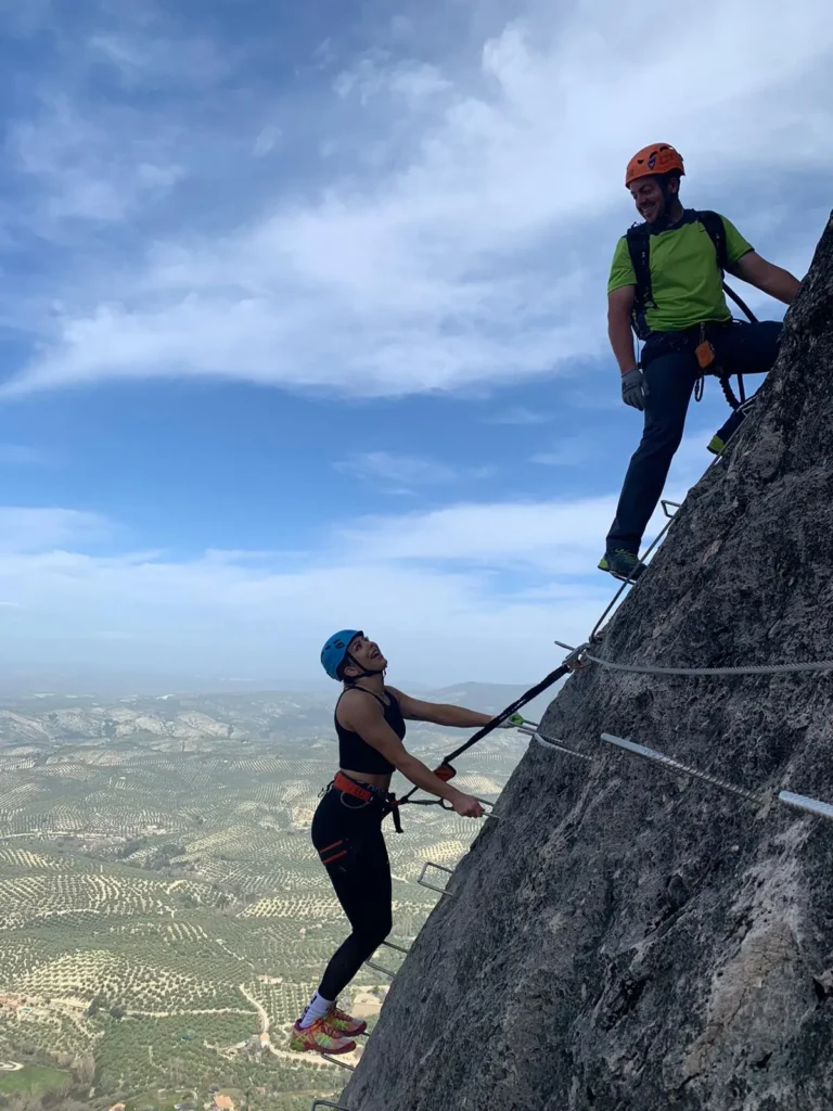Guía asistiendo a participante en vía ferrata vertical